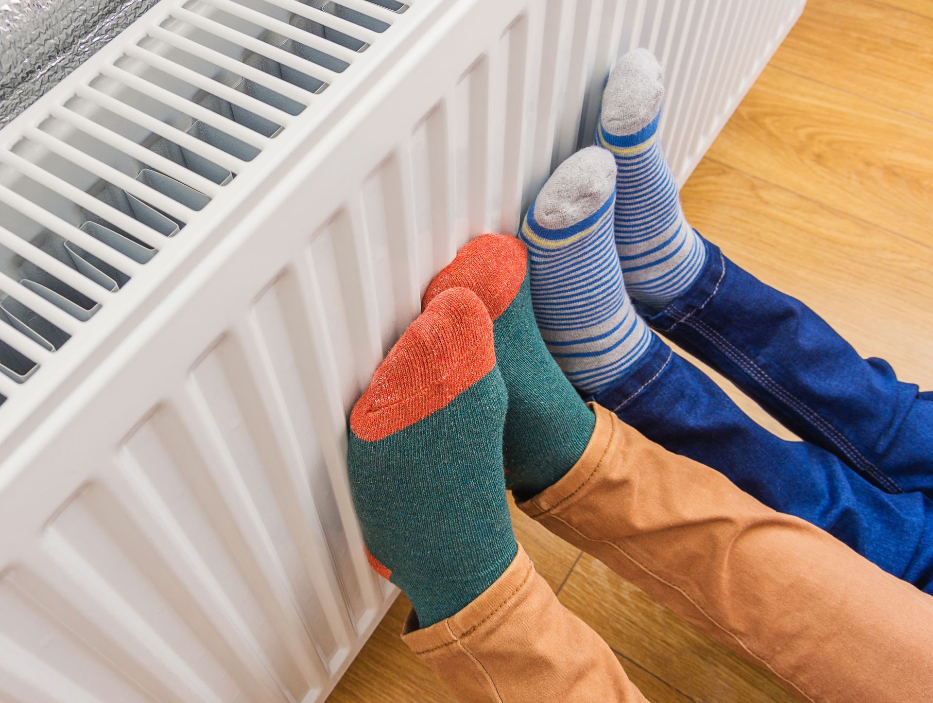 Des personnes en chaussettes qui posent leurs pieds sur un radiateur.