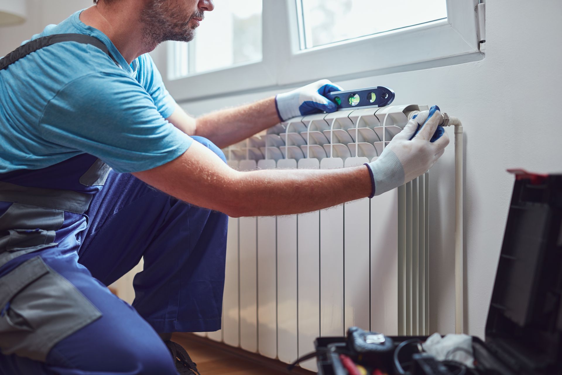 Un plombier-chauffagiste qui installe un radiateur.