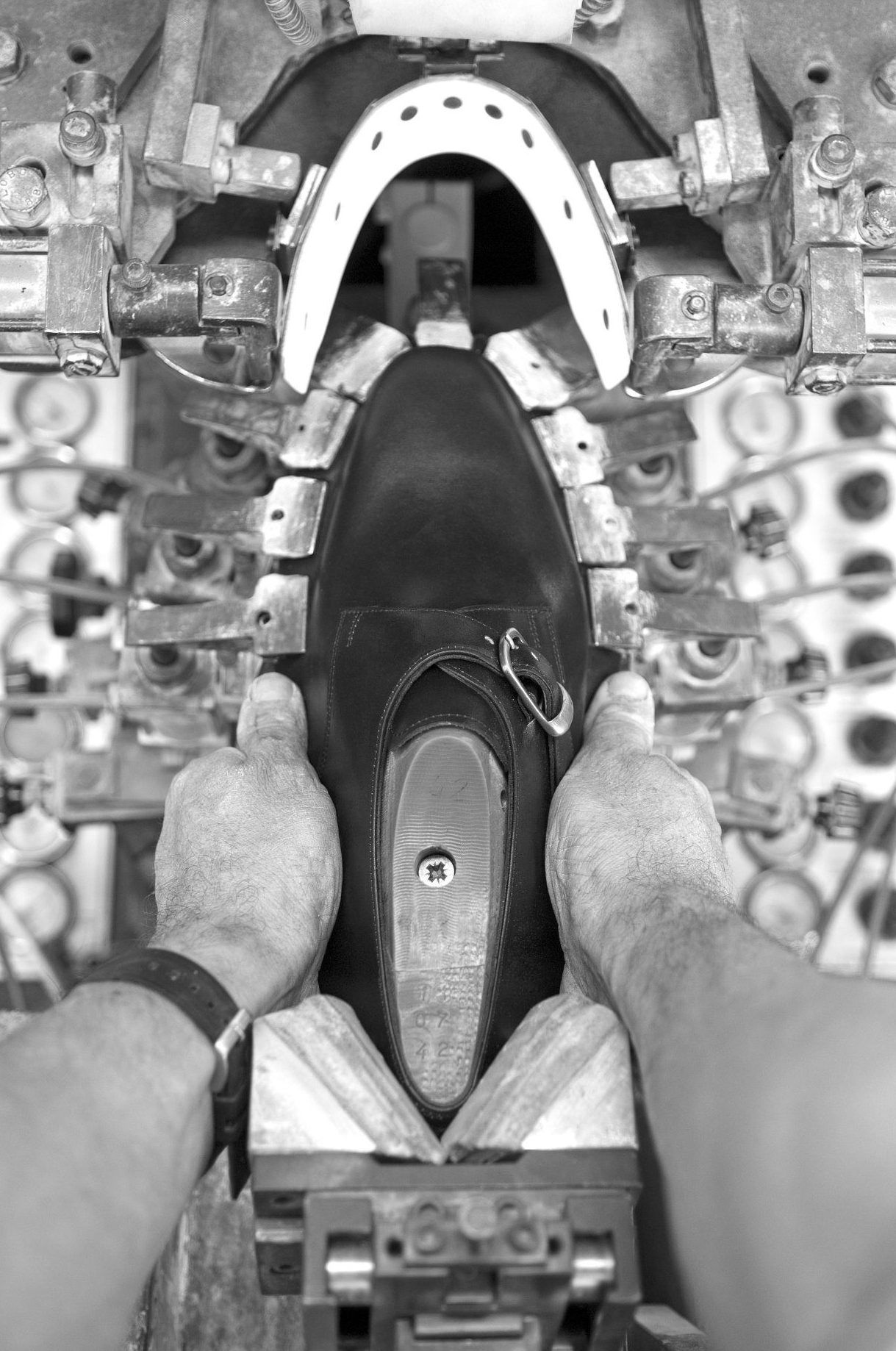 Pieds chaussés de noir sur le gouvernail ou le mécanisme de direction à pédales d'un bateau, vus de dessus.