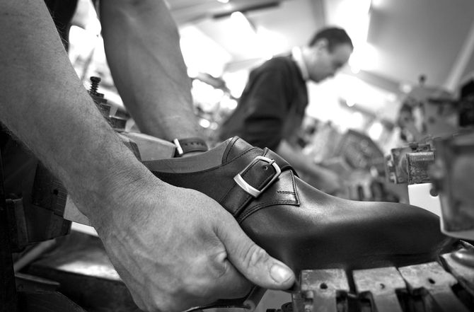 Des mains ajustent une chaussure habillée sur un établi dans un atelier de réparation de chaussures