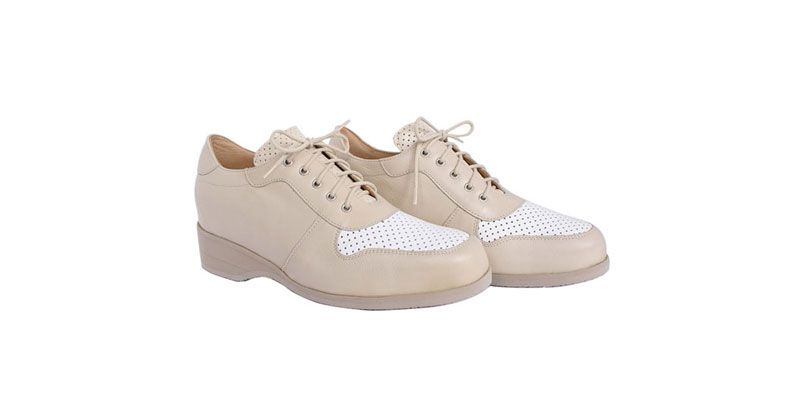 Paire de chaussures beiges à lacets avec bout perforé blanc sur fond blanc