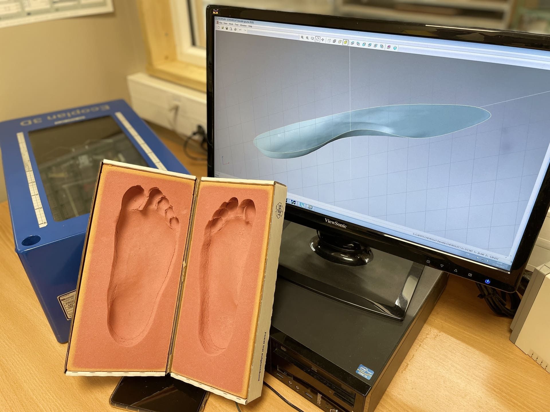 Modèle de plante de pied imprimé en 3D à côté d'un écran d'ordinateur affichant un scan 3D du pied correspondant