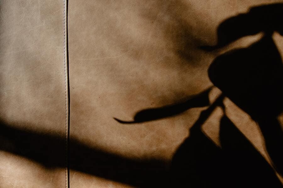 Ombre d'une personne sur un mur en tissu beige, la main et le bras levés.