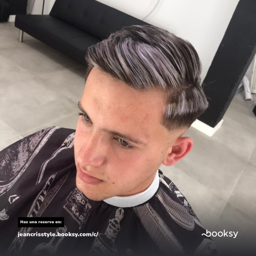 Hombre con un corte de pelo elegante, con reflejos plateados, vistiendo una capa de salón.