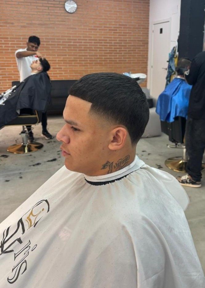 Hombre en la silla de barbero con un corte de pelo fresco; entorno de barbería.