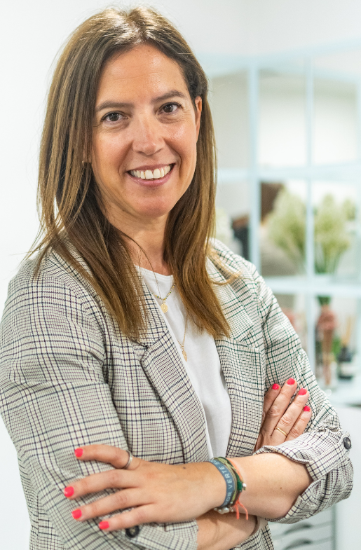 Una mujer con una chaqueta a cuadros sonríe con los brazos cruzados.