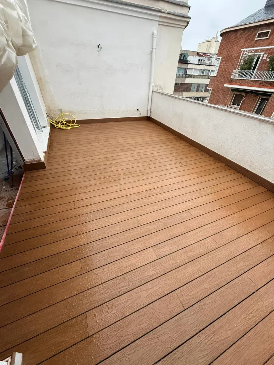 Tarima exterior instalada en una terraza con plantas y luz de sol