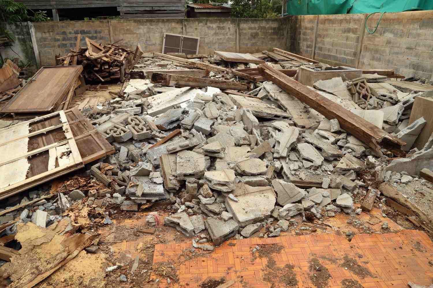 Escombros de hormigón derrumbados y madera rota apilados en una obra en construcción dañada.