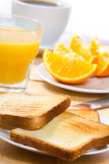 Tostadas, jugo de naranja y una taza de café sobre una mesa