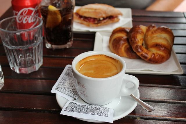 Una lata de Coca Cola se encuentra junto a una taza de café.