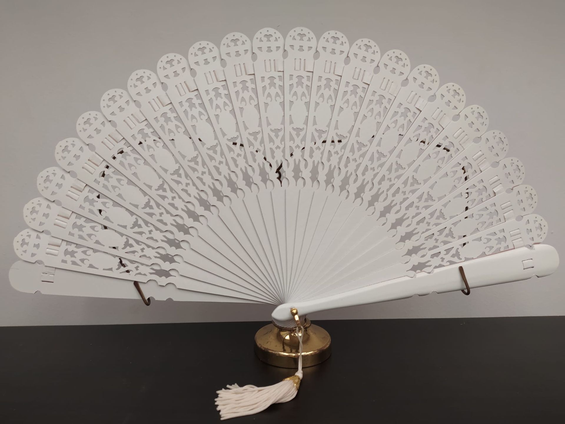 Un abanico blanco con una borla está sobre una mesa.
