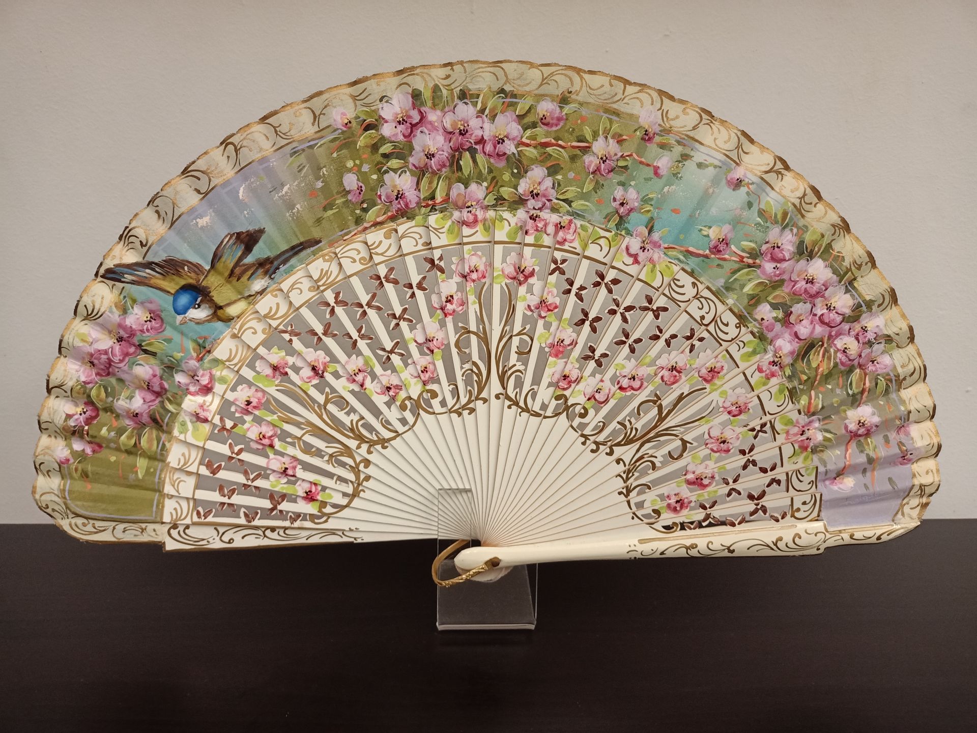 Un abanico con flores rosas y un pájaro encima.