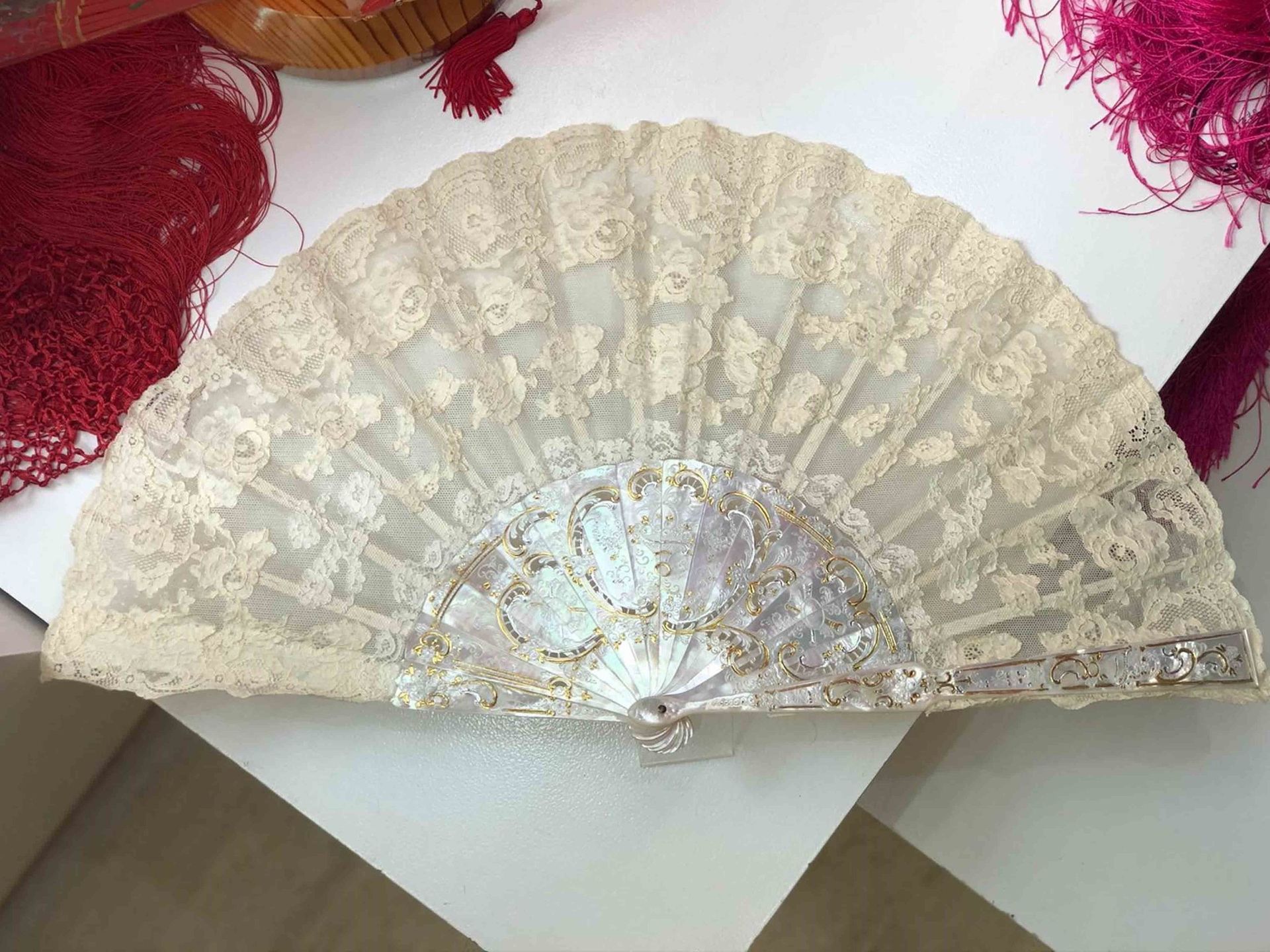 Un abanico de encaje blanco está sobre una mesa blanca.
