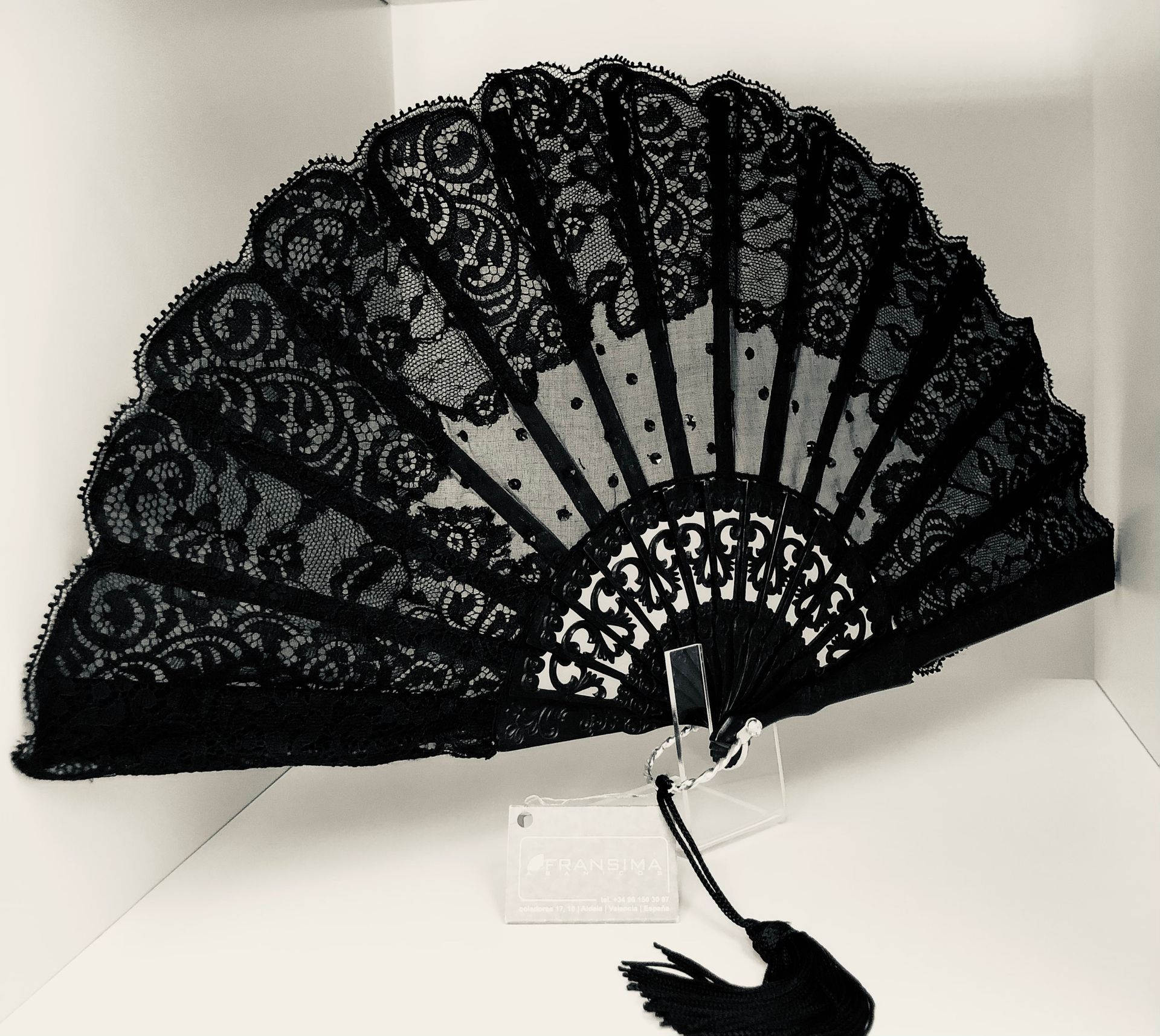 Un abanico de encaje negro reposa sobre una superficie blanca.