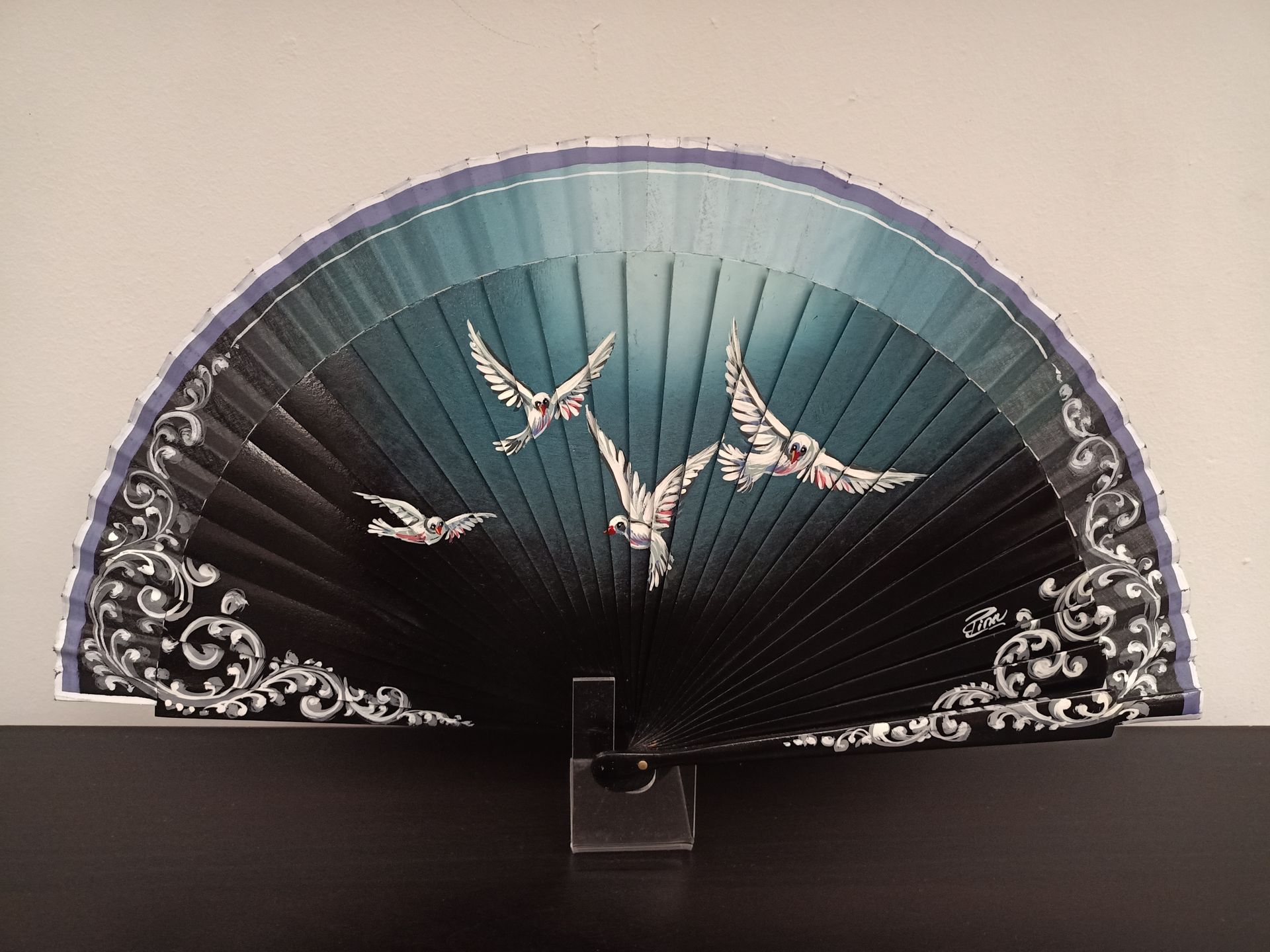 Un abanico con pájaros está sobre una mesa.