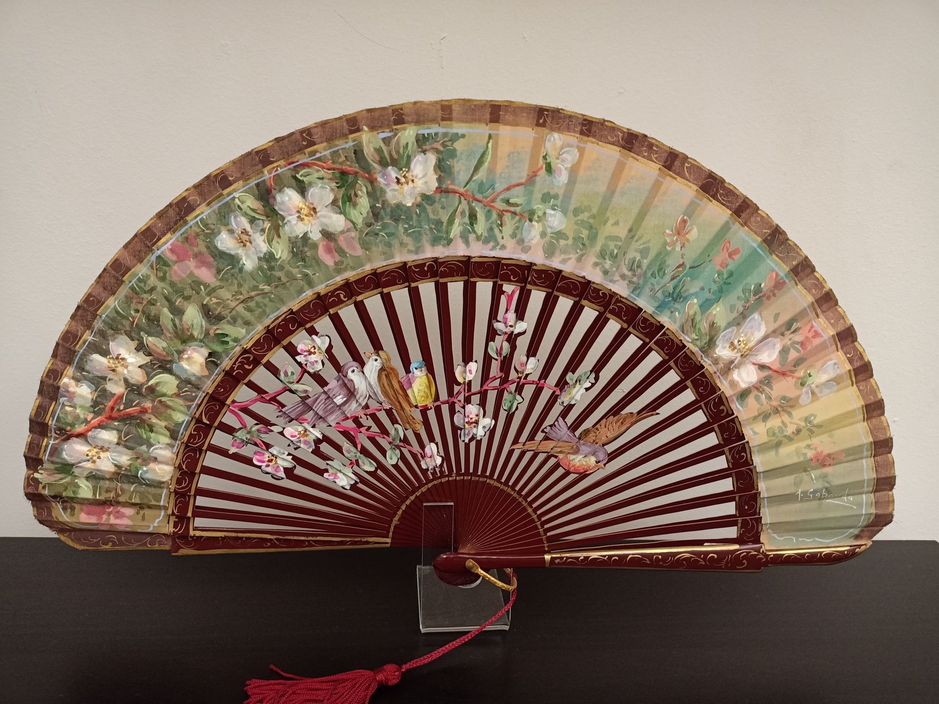 Un abanico con flores está sobre una mesa.