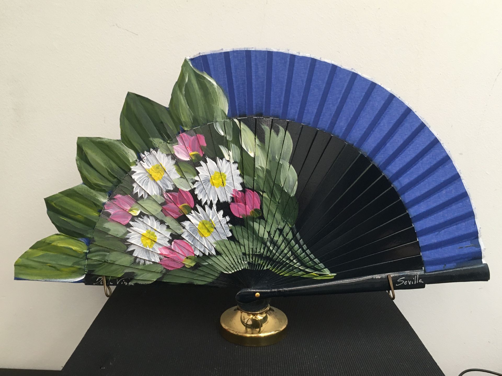 Un abanico azul y negro con flores pintadas.