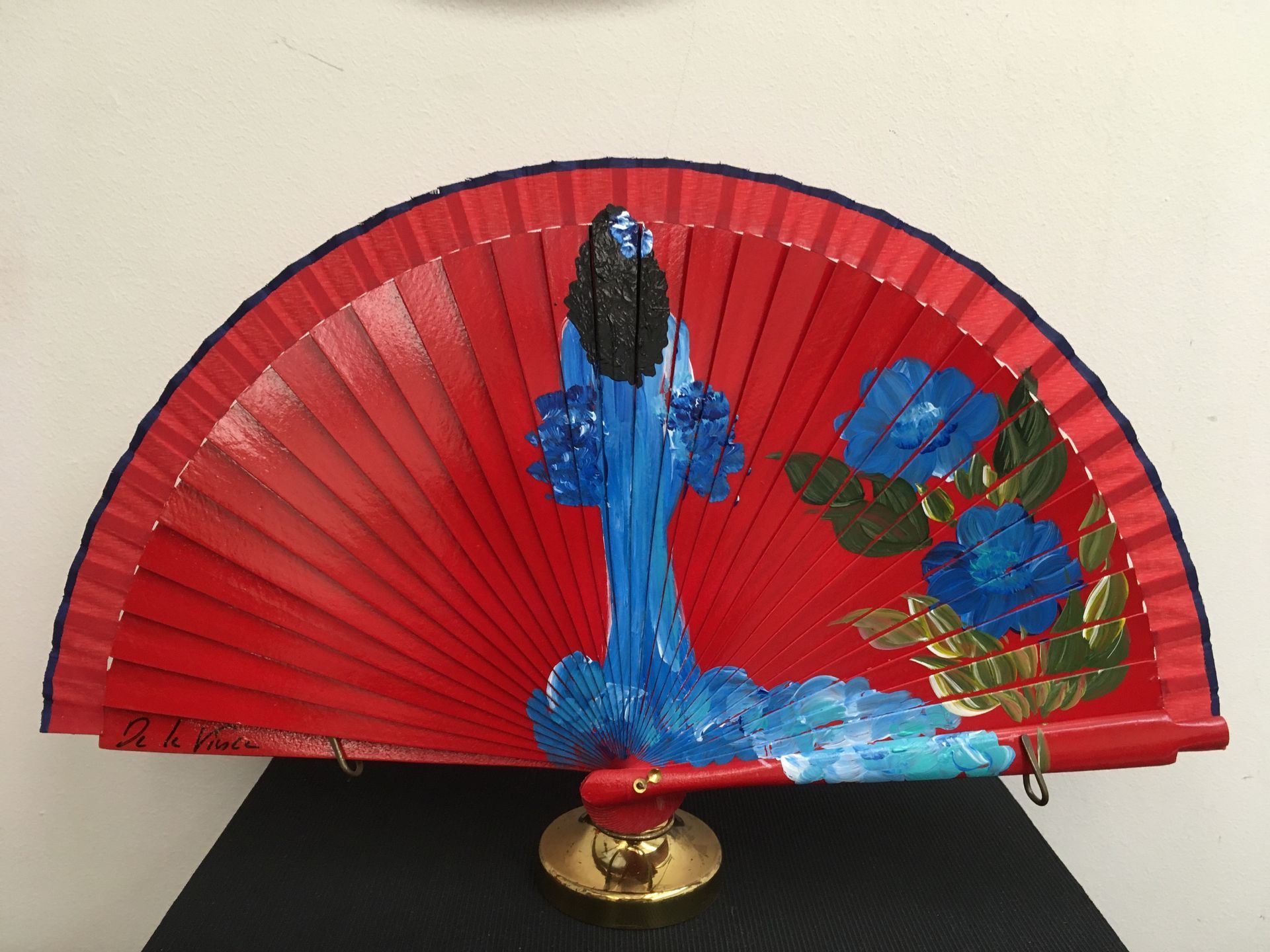 Un abanico rojo con una cascada y flores pintadas en él.