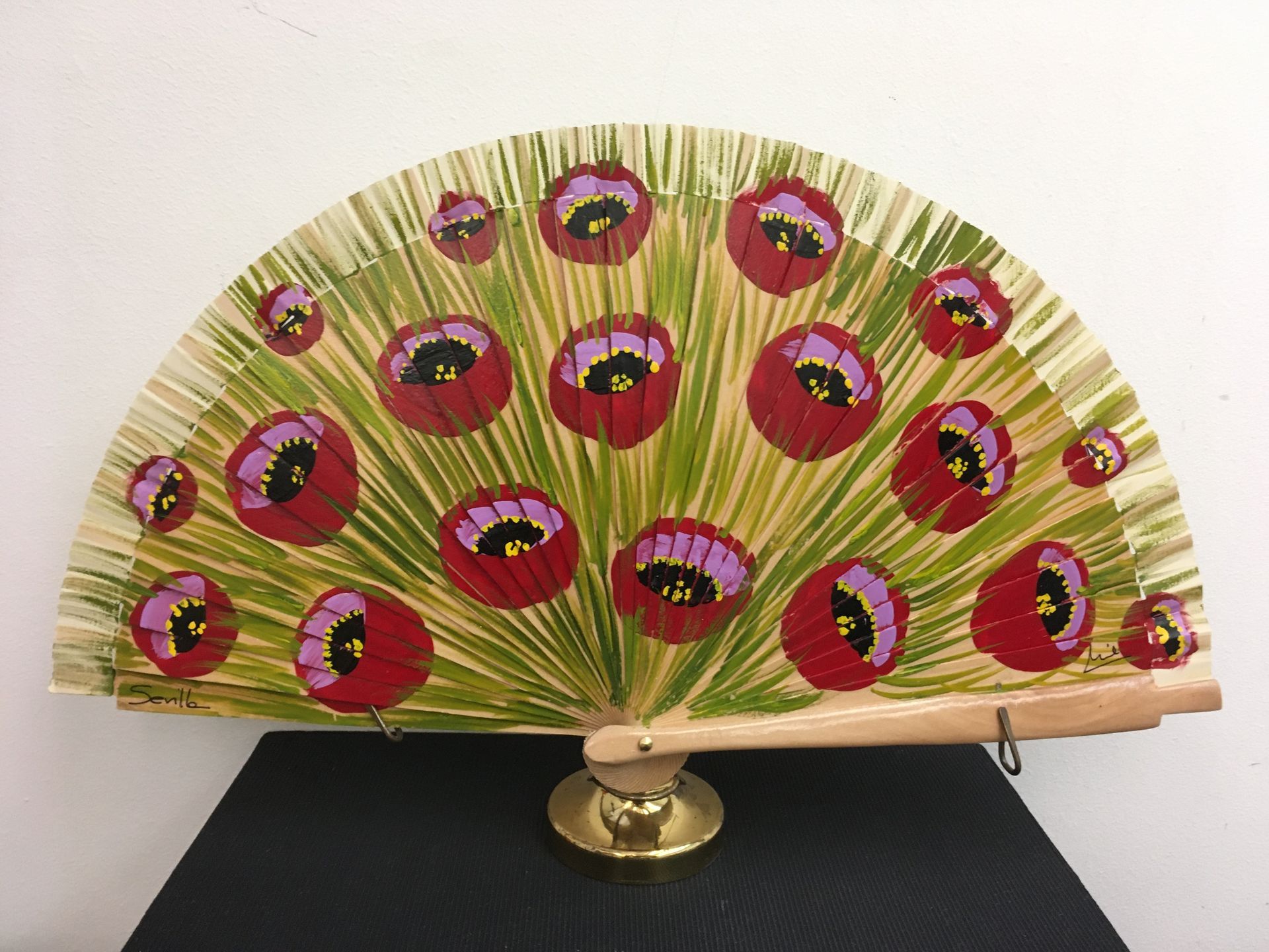 Un abanico con flores rojas y moradas pintadas.