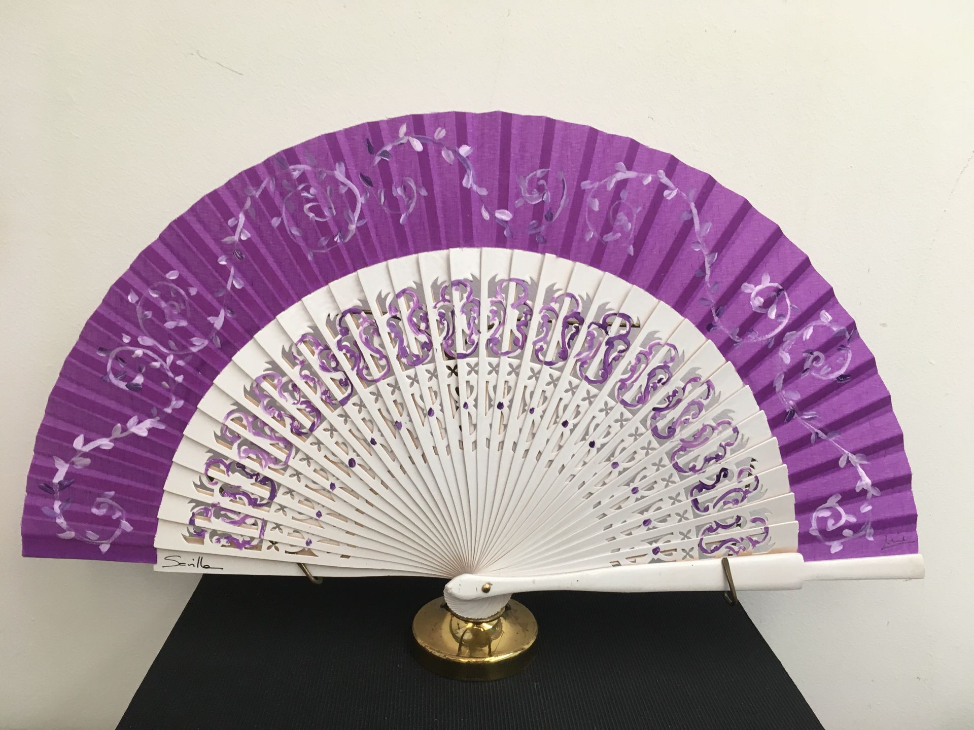 Un abanico morado y blanco está sobre una mesa.
