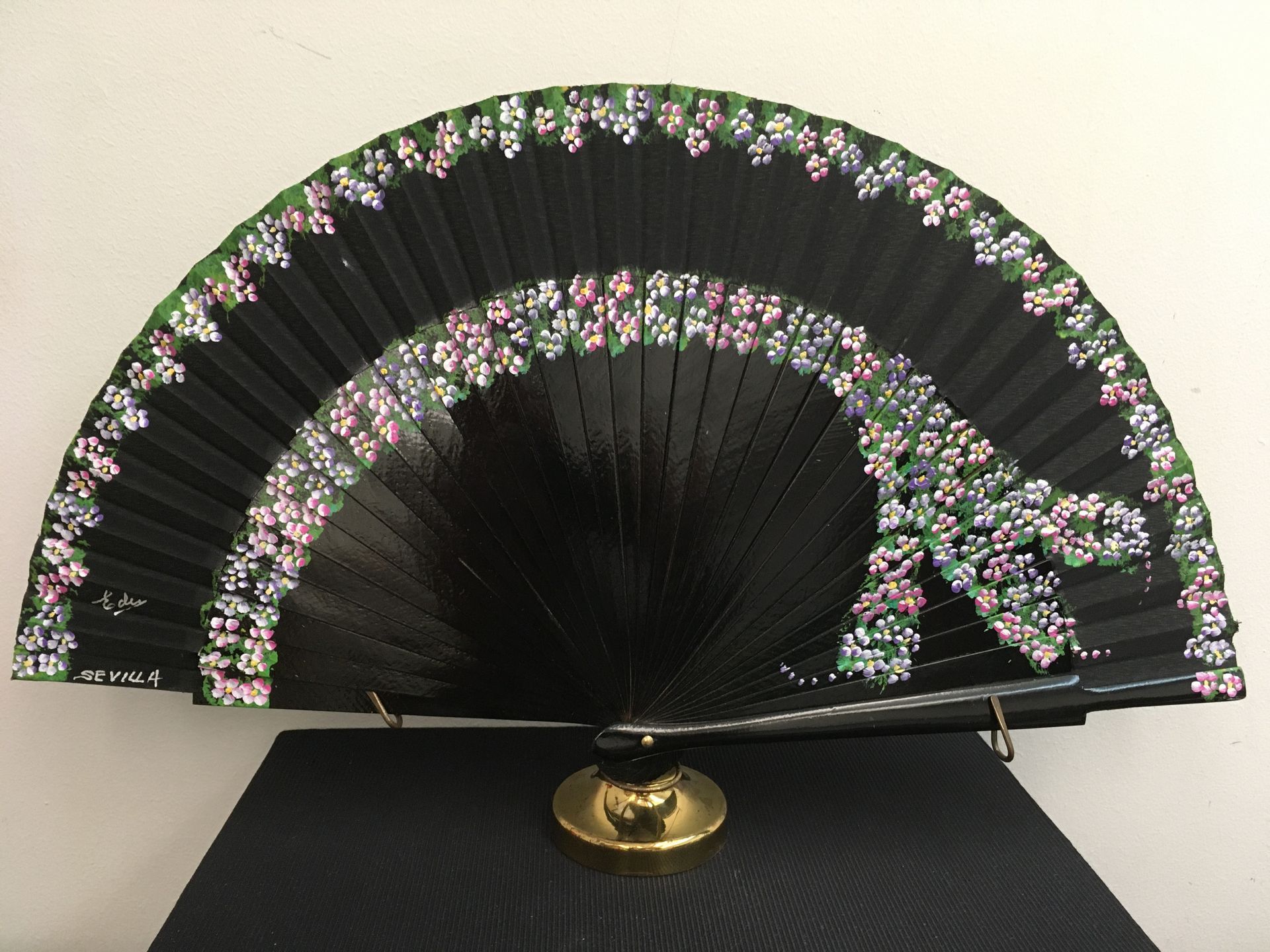 Un abanico negro con flores pintadas.