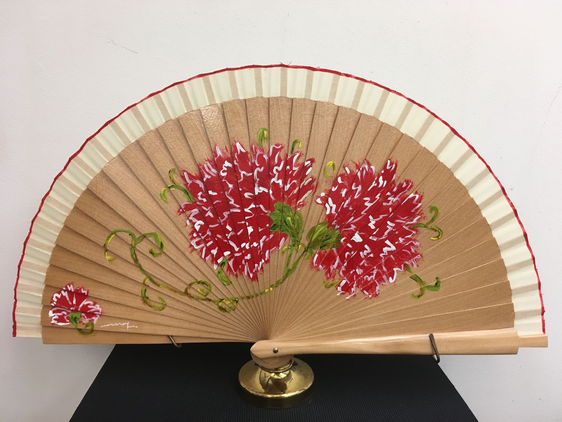 Un abanico con flores rojas y blancas pintadas.