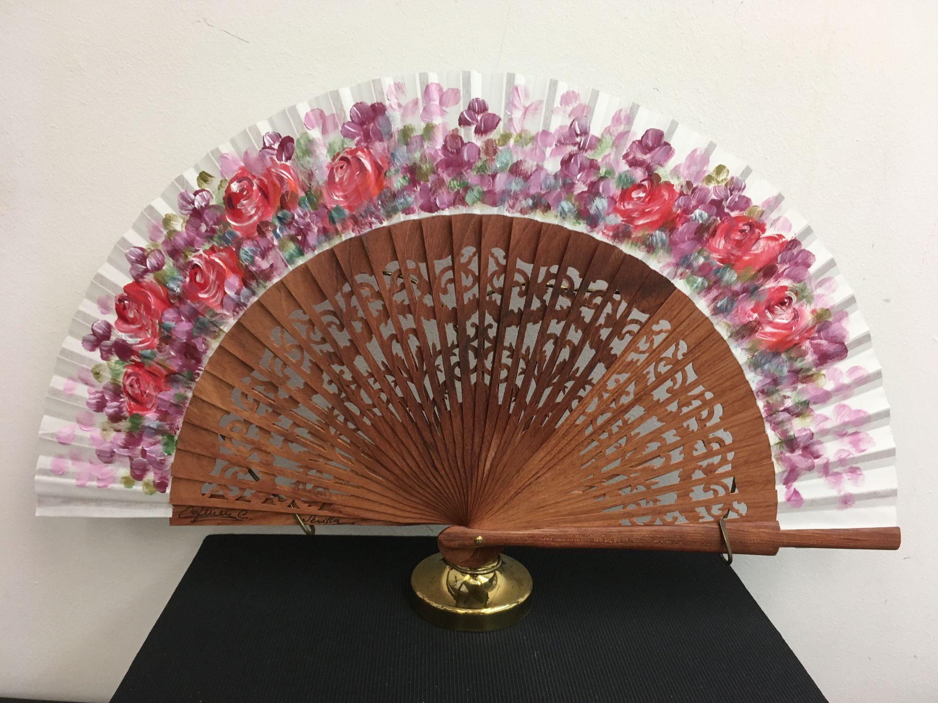 Un abanico con flores está sobre una mesa.