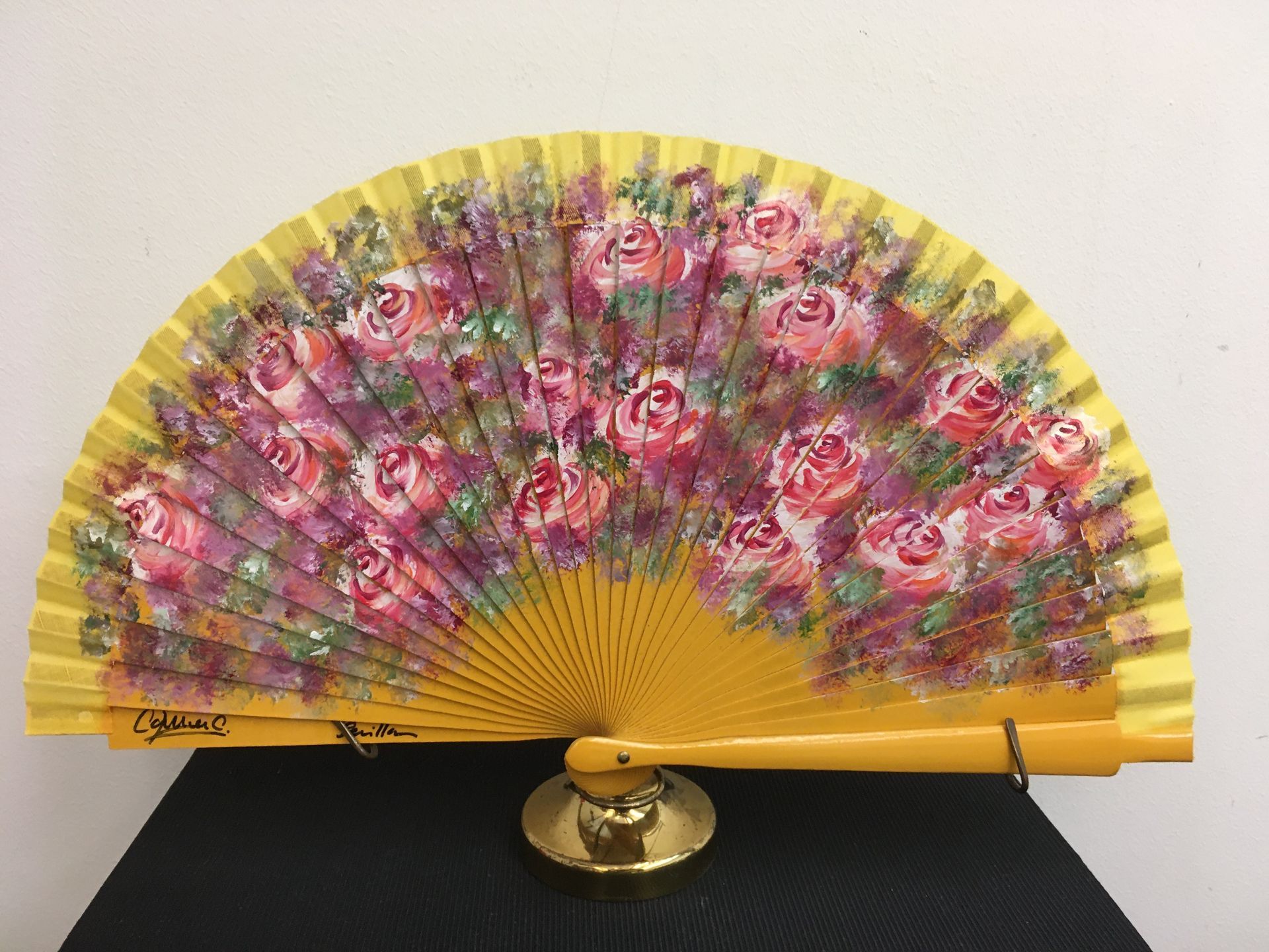 Un abanico amarillo con rosas rosadas.