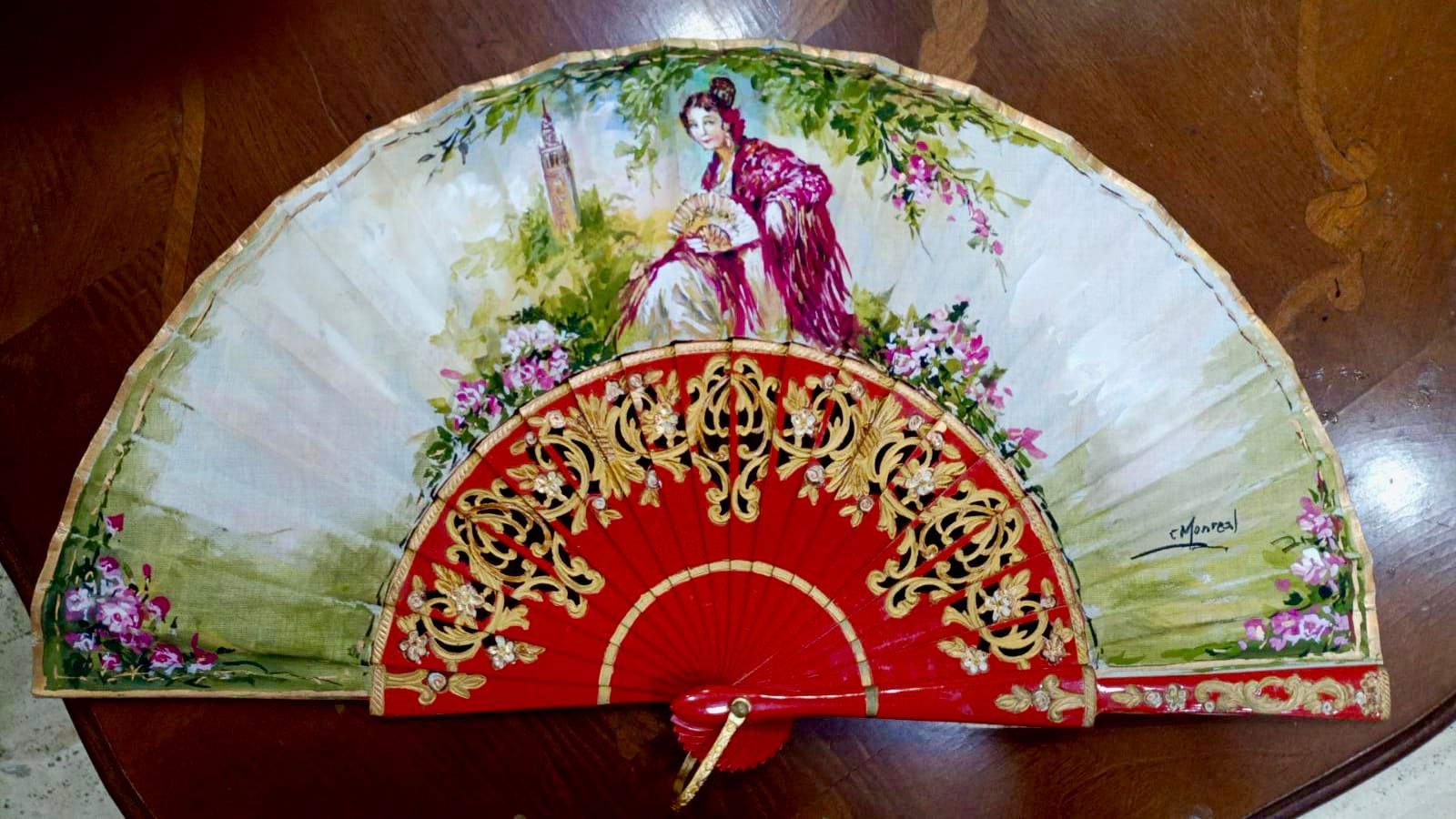 Un abanico rojo y blanco con la imagen de una mujer.