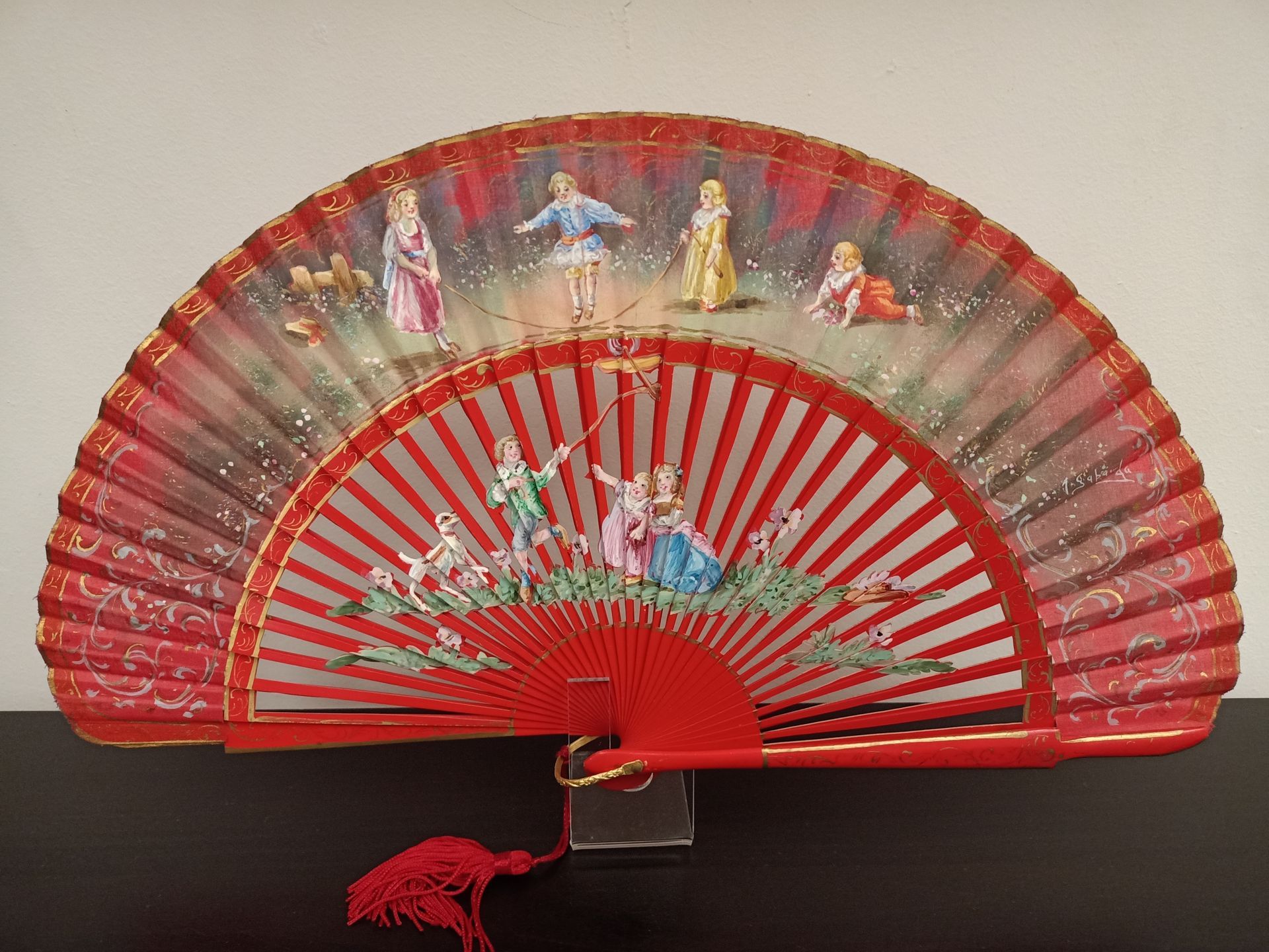 Un abanico rojo con una pintura de personas en él.