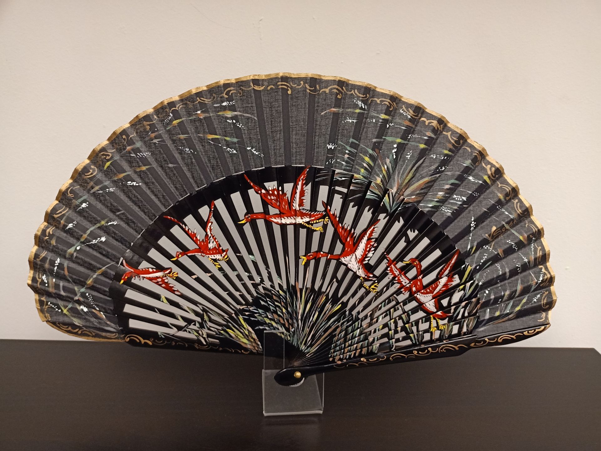 Un abanico blanco y negro con pájaros rojos.
