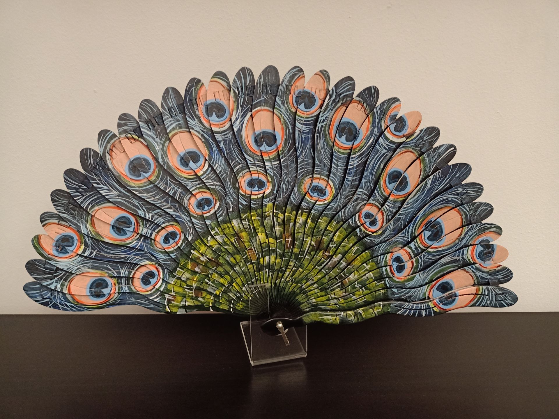 Un abanico con plumas de pavo real está sobre una mesa.