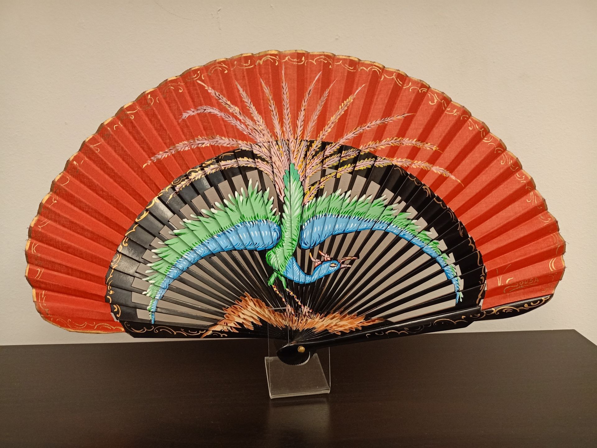 Un abanico rojo con un diseño de pavo real.