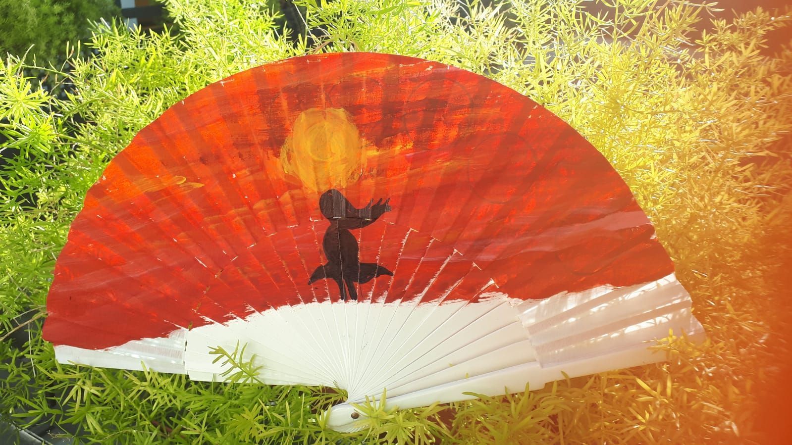 Un abanico rojo y blanco con la silueta de una persona en él.