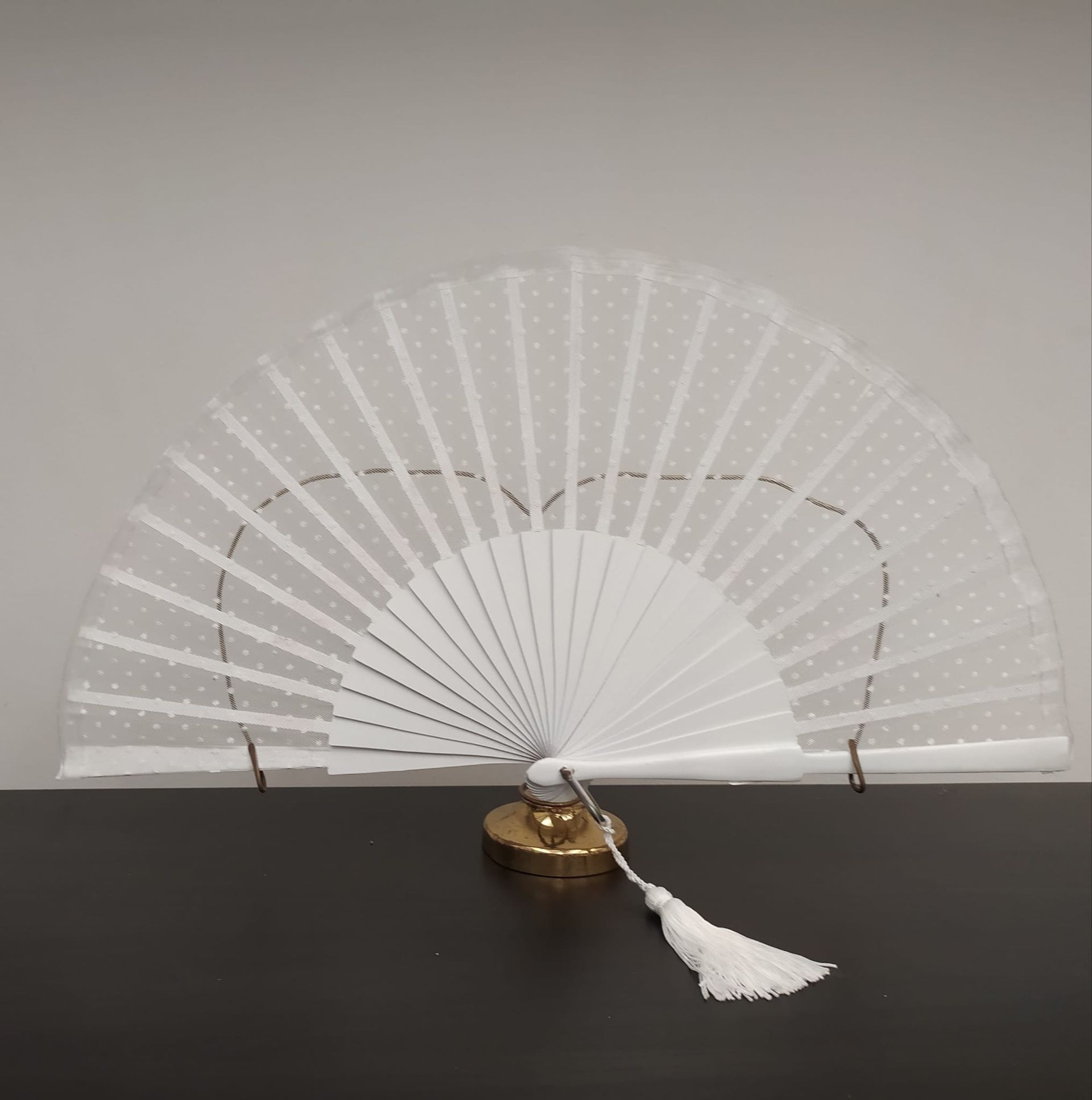 Un abanico blanco con una borla está sobre una mesa.