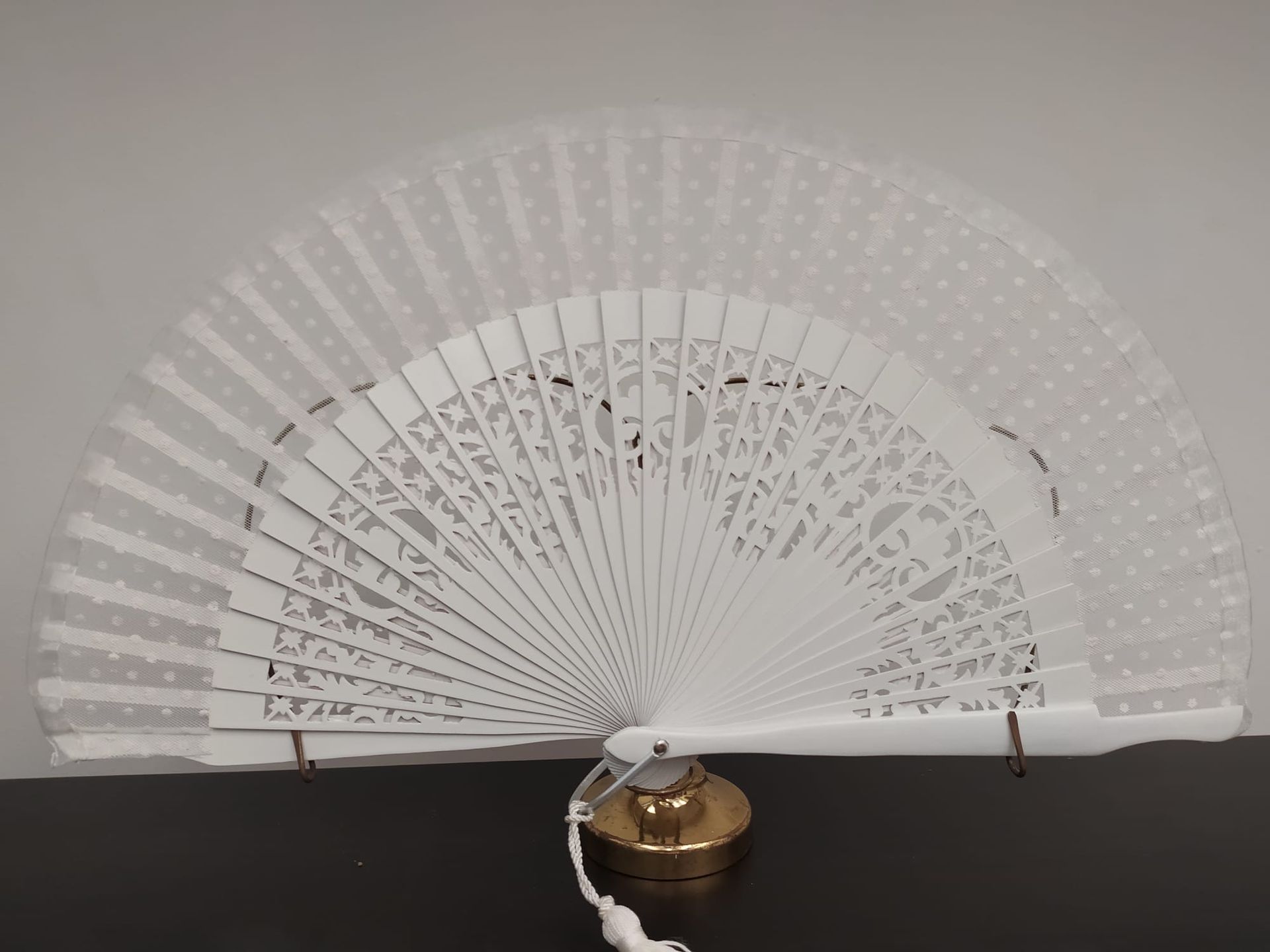 Un abanico blanco está sentado sobre una mesa negra.