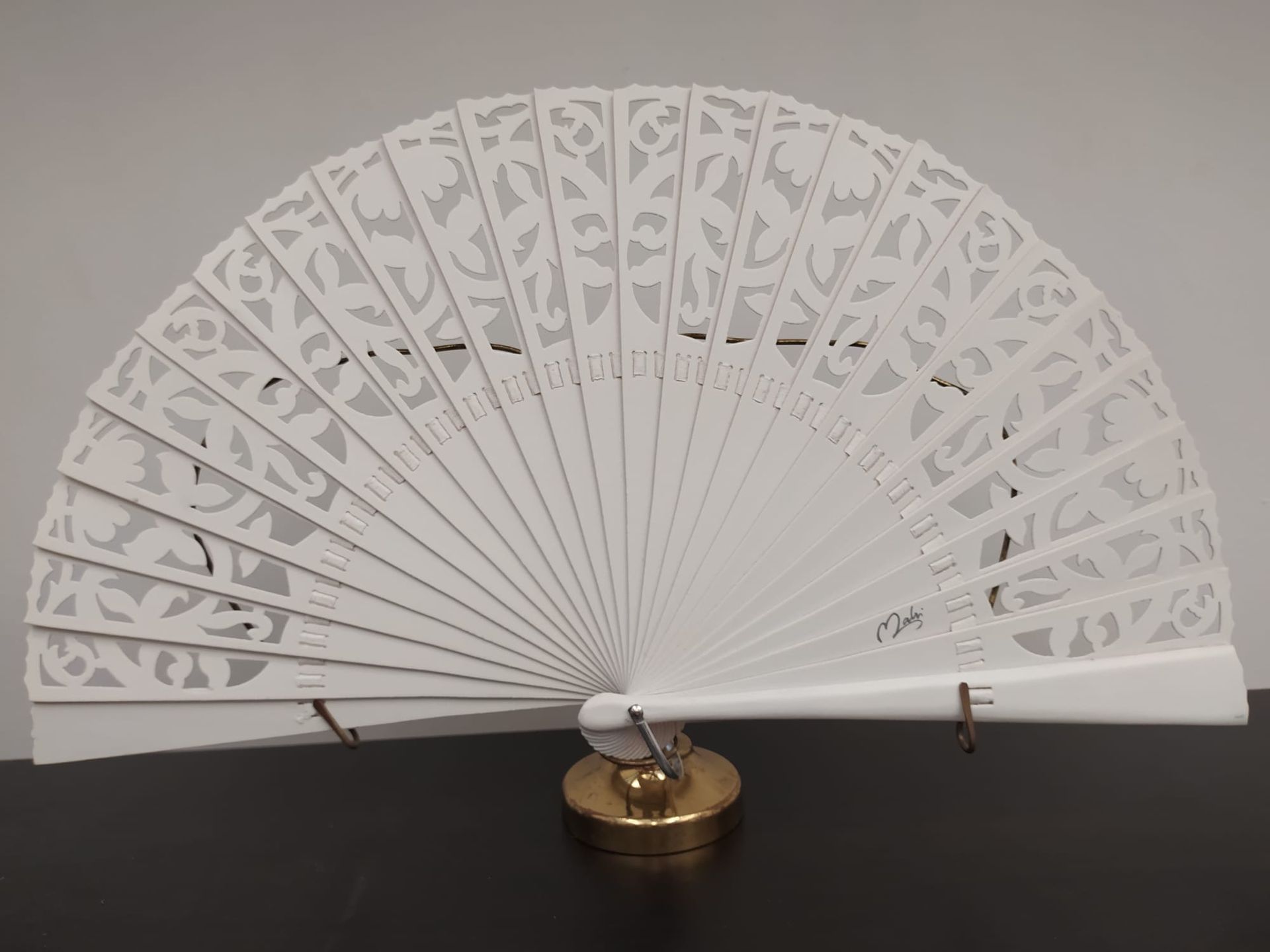 Un abanico blanco está sentado sobre una mesa negra.