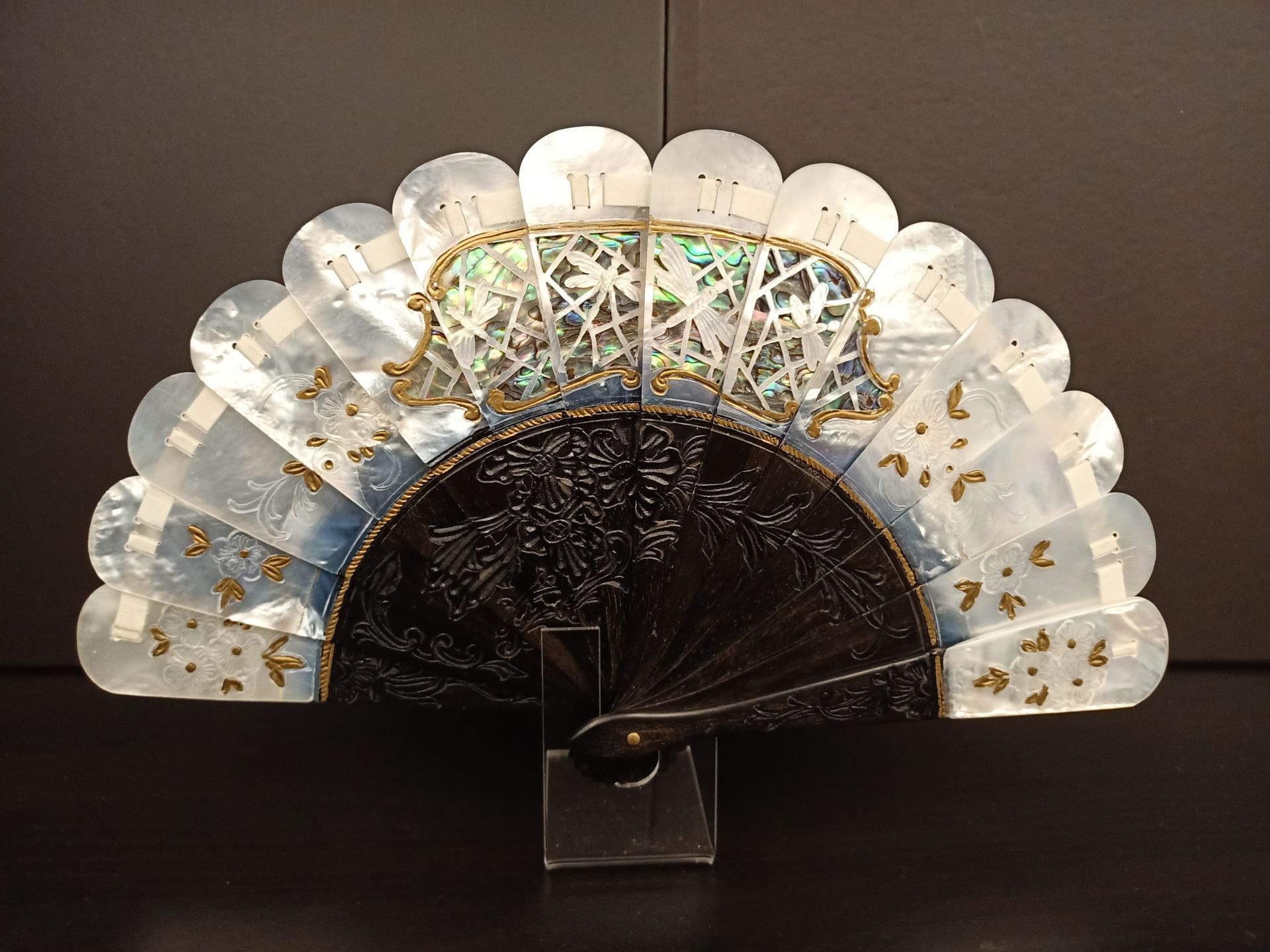 Un ventilador blanco y negro está sentado en un soporte.