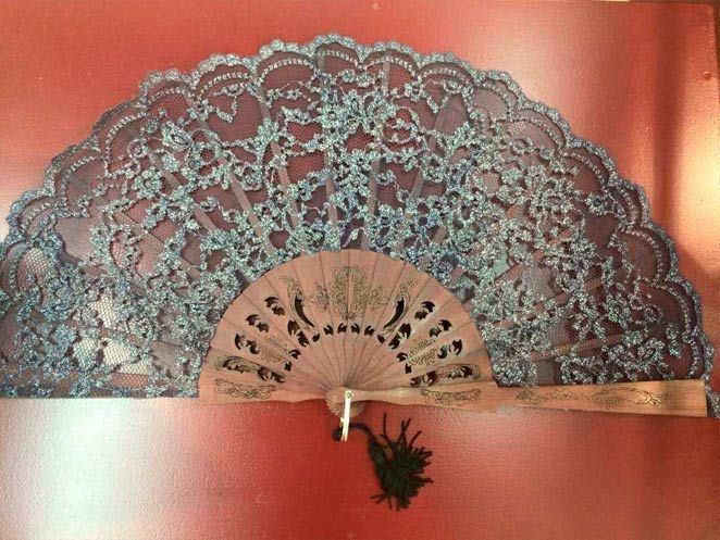 Un abanico está colgado en una pared roja con una borla.