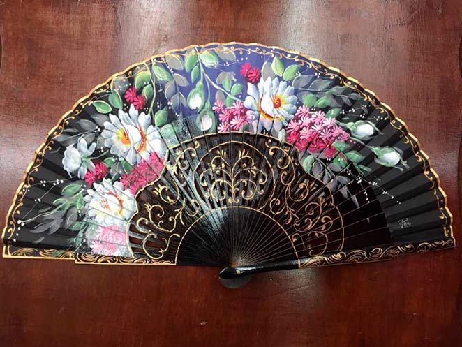 Un abanico negro con flores pintadas.