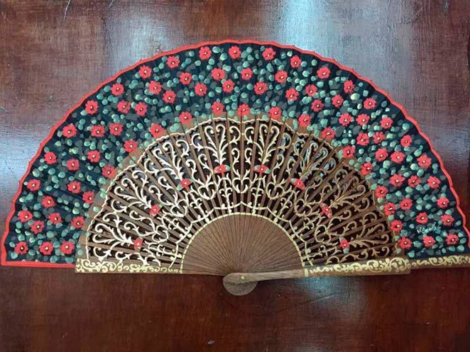Un abanico con flores rojas y verdes.