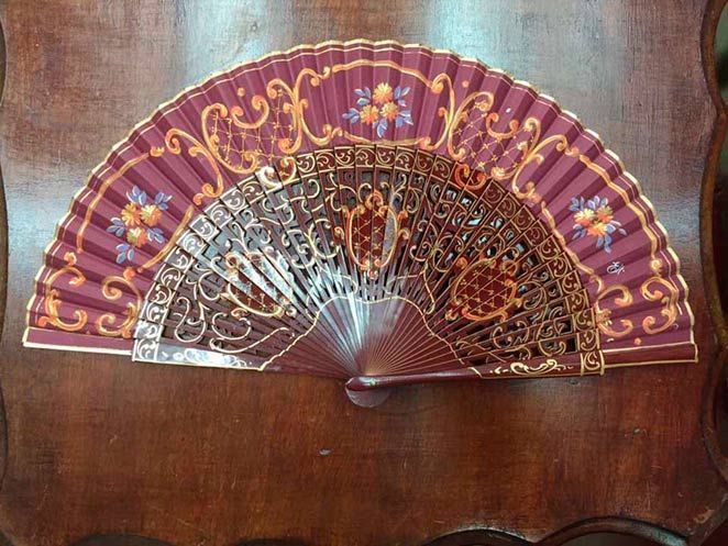 Un abanico morado y dorado está sobre una mesa de madera.
