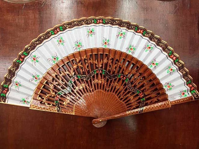 Un abanico con flores está sobre una mesa de madera.