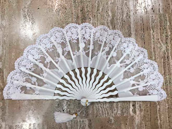 Un abanico de encaje blanco reposa sobre una mesa de mármol.