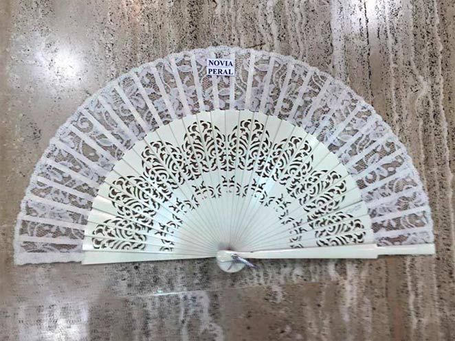 Un abanico blanco con un estampado está sobre una mesa.