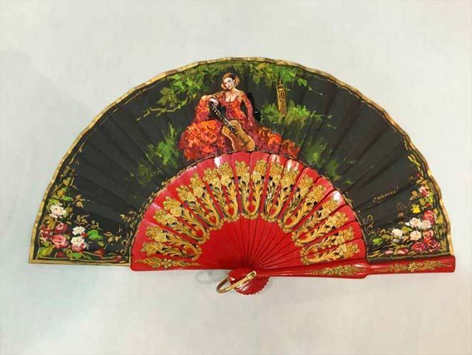 Un abanico rojo y negro con una mujer en él.