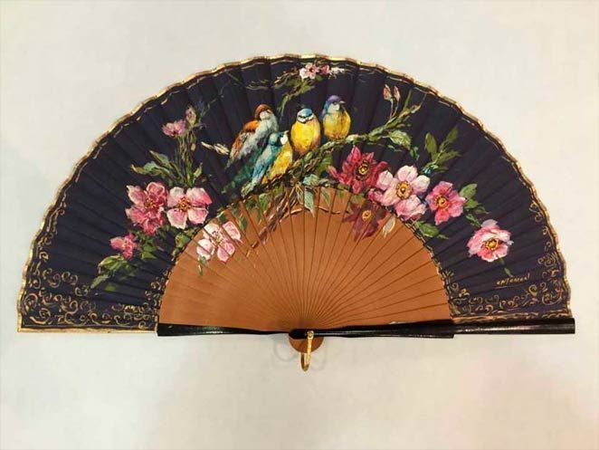 Un abanico con flores y pájaros pintados.