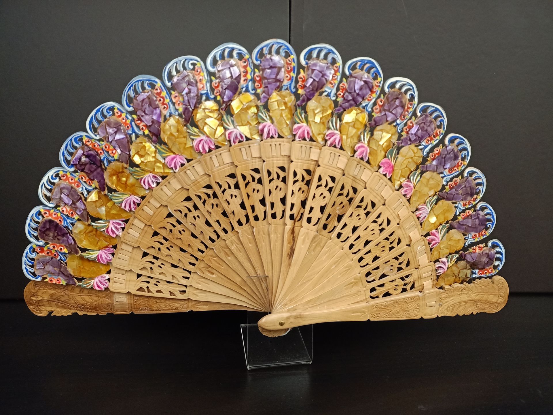 Un abanico con flores moradas y doradas.