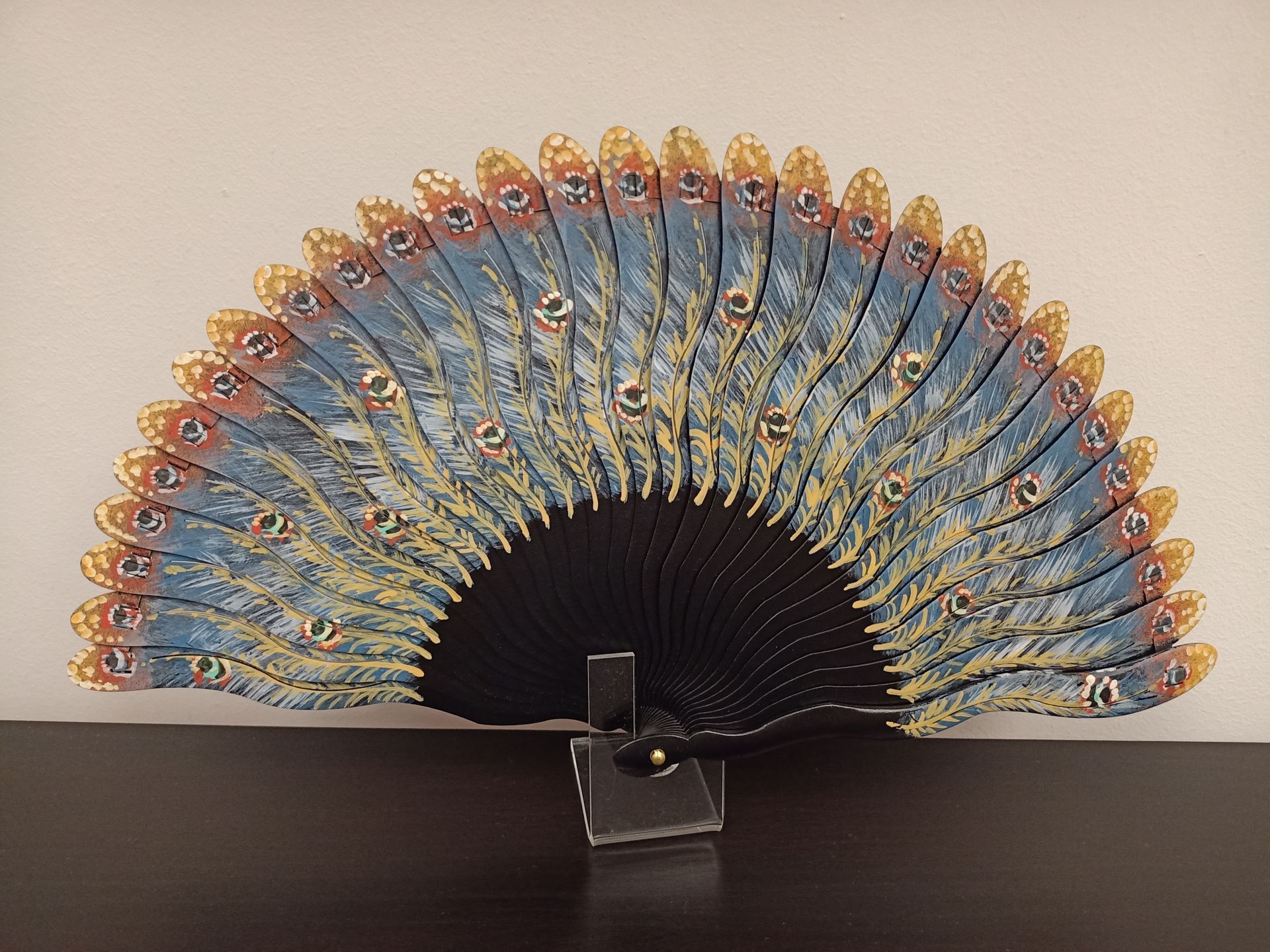 Un abanico azul y dorado está sentado en una mesa.