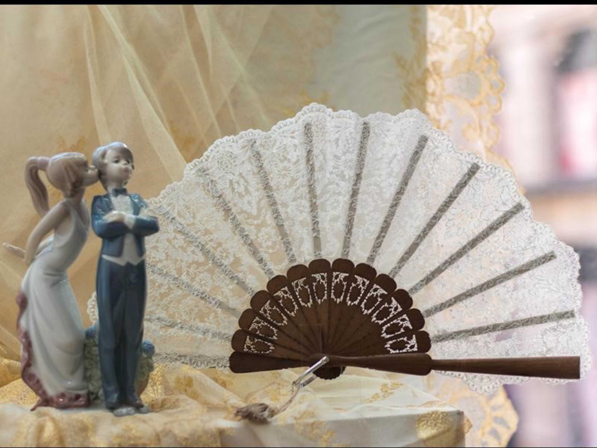 Una figura de novios junto a un abanico.